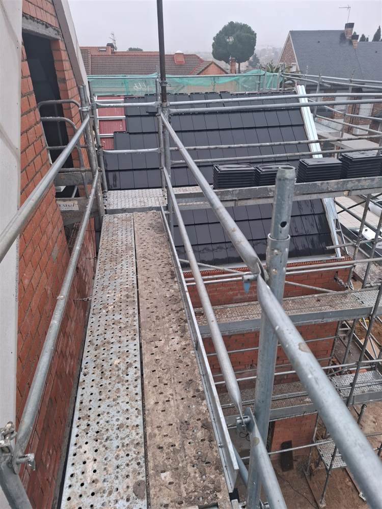 Colocación de tejas nuevas en una cubierta con andamio, obra de tejado en Colmenar de Oreja